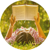 a woman lays in long grass reading